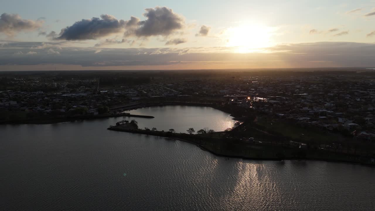 Aerial view of a sunset over an urban landscape with a waterbody reflecting the fading sunlight in Federacion, Entre Ríos, Argentina