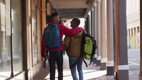 back view of mixed race gay male couple talking and smiling in the street