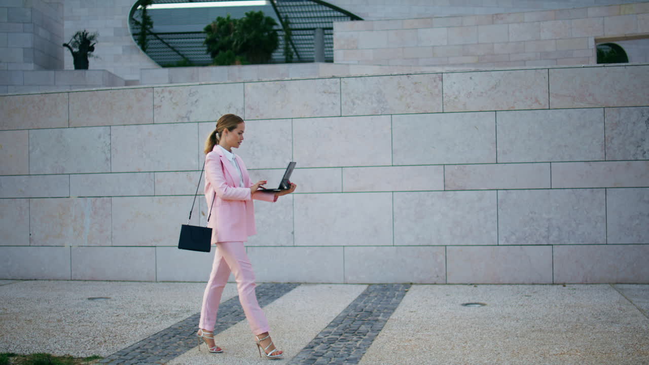 Confident freelancer working go holding laptop. Woman walking looking computer