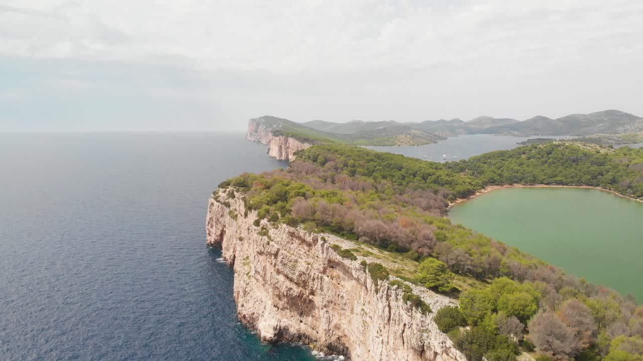 una antena de aspecto profesional de la línea del acantilado de la isla kornat en croacia, volando sobre los árboles del acantilado.