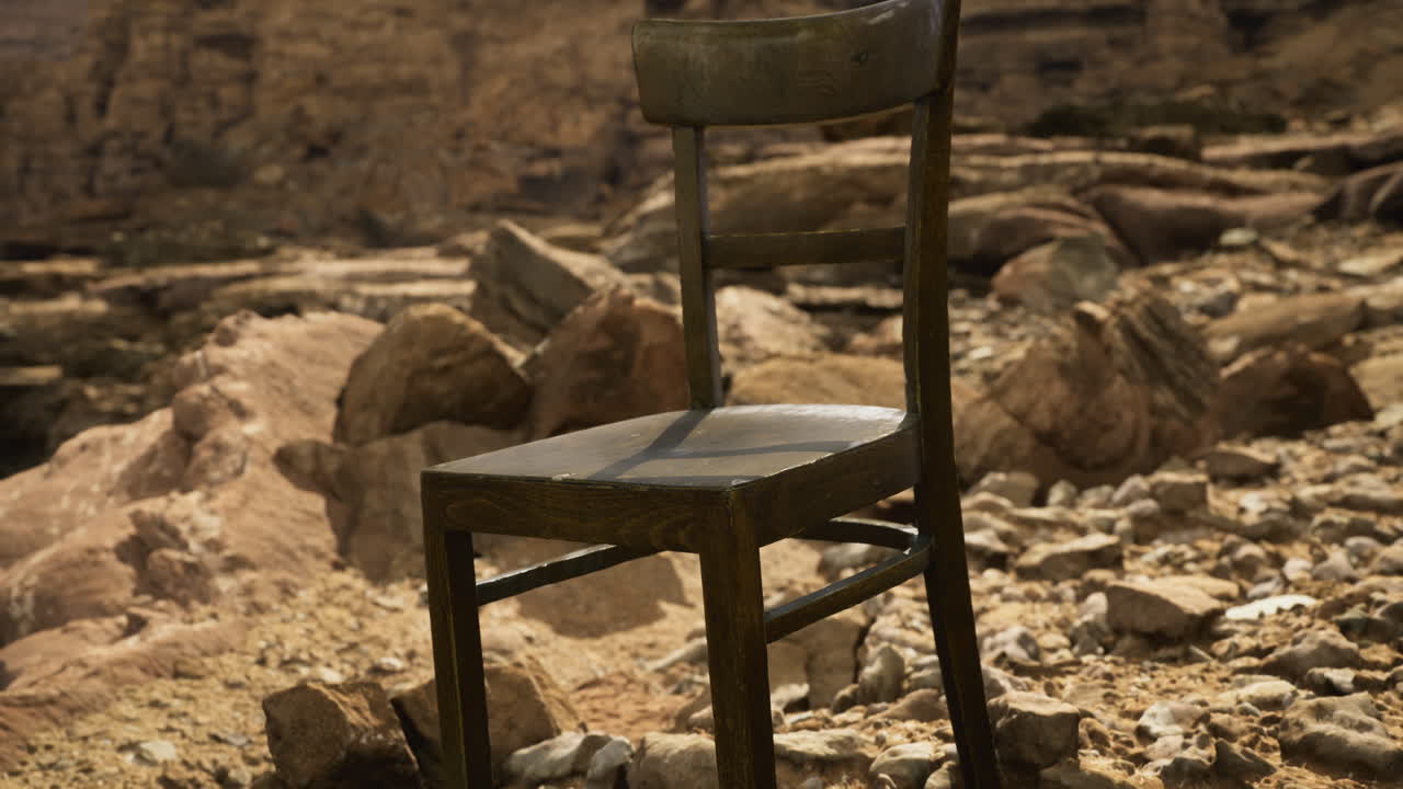Lonely wooden chair on rocky terrain near a cliff edge under bright sun