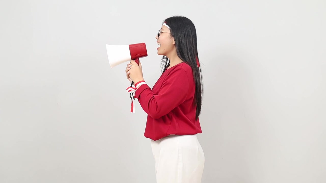 年輕印尼女性慶祝印尼獨立日，側身用擴音器大聲呼喊並發布公告。
