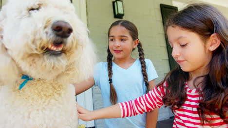 Dos-Niñas-Acariciando-Al-Perro-De-La-Familia-En-El-Porche-De-La-Casa