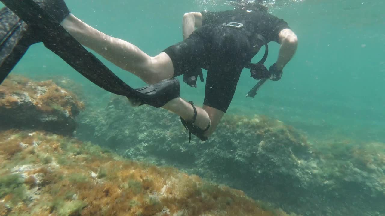 Follow shot of spearfisher snorkeling in the mediterranean sea in shallow waters
