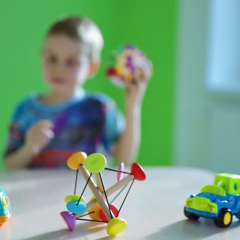 educational games.little boy playing alone with a toy. bright toy cars and wooden plaything on the wooden table on blur boy background.