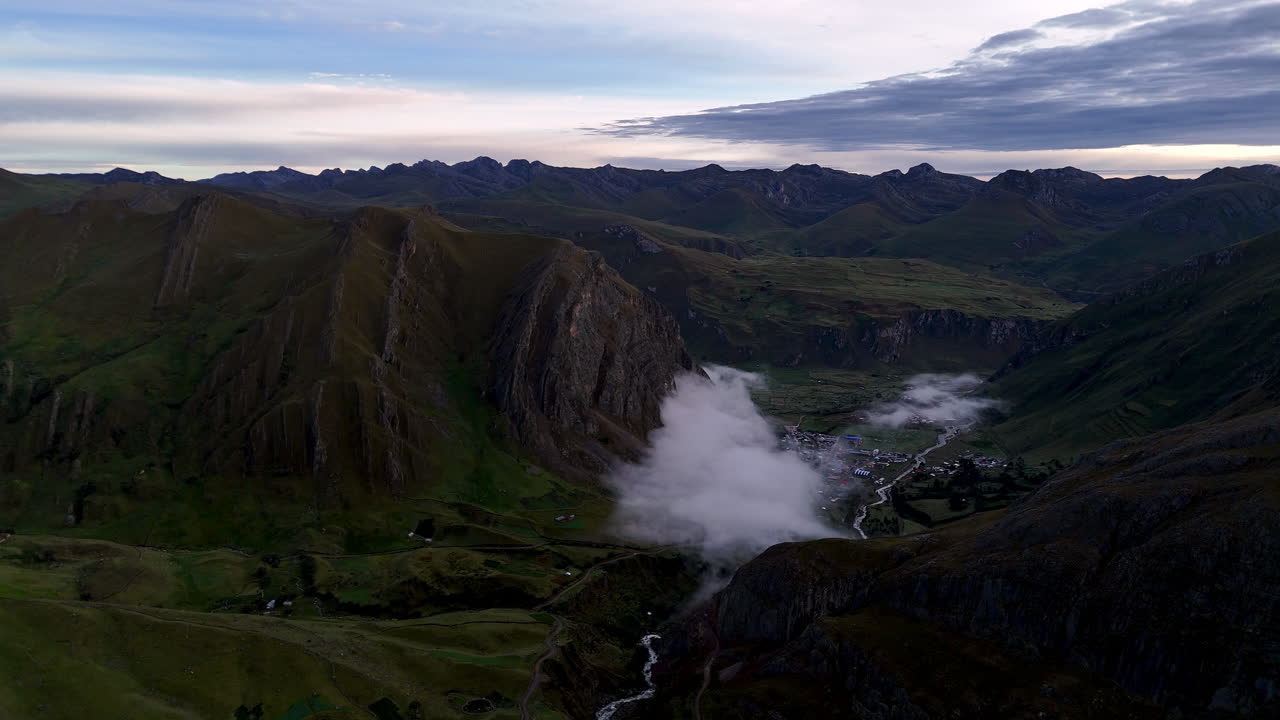 Cinematic aerial view of snowy Andes mountains in Peru with glaciers, rocky cliffs, and hidden blue alpine lake under misty clouds, dramatic landscape and natural travel destination