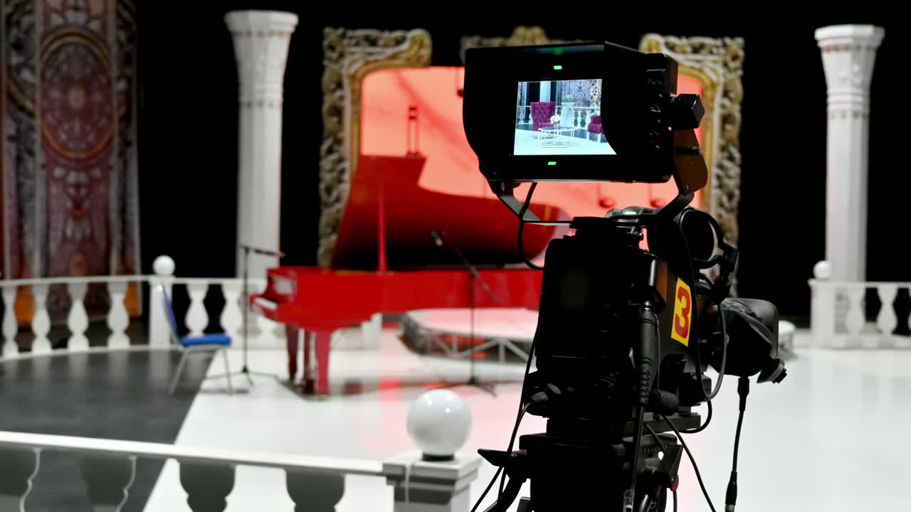 Professional camera filming a red piano on the backstage of a TV set