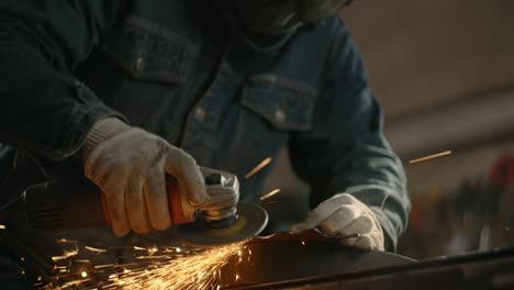 locksmith sands the edges of a metal detail by electric grinder with a lot of sparks in slow motion, metalwork at workshop, 4k 60p prores hq