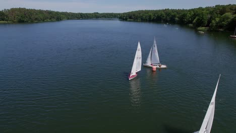 Sailboats-race-on-a-lake,-boat-turning,-parallax-drone-shot
