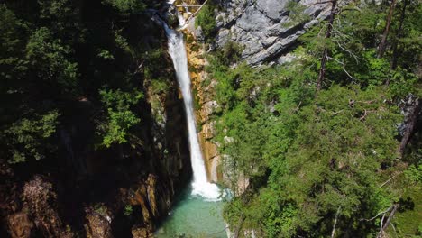 fotografia estável de um drone de uma enorme cachoeira cercada por montanhas rochosas e florestas