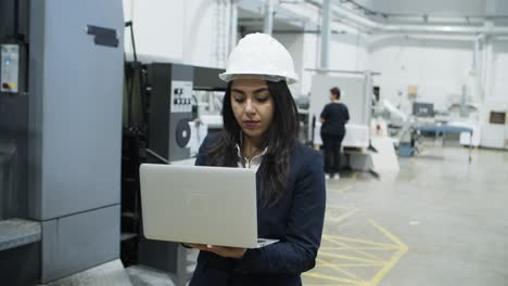 Focused-project-manager-walking-with-laptop-at-factory