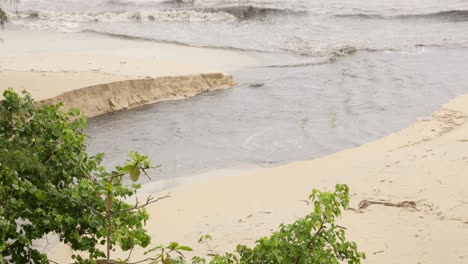 Close-up-view-of-a-stream-pouring-out-into-the-ocean-during-a-rain-storm