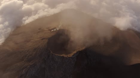 Drone-shot-circling-an-active-Volcano-crater,-above-a-sunny-mountain-summit