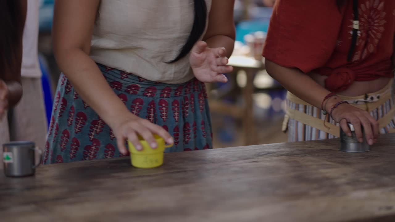 People clapping and interacting with mugs on a wooden table