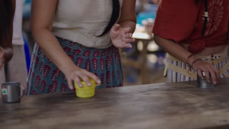 people clapping and interacting with mugs on a wooden table