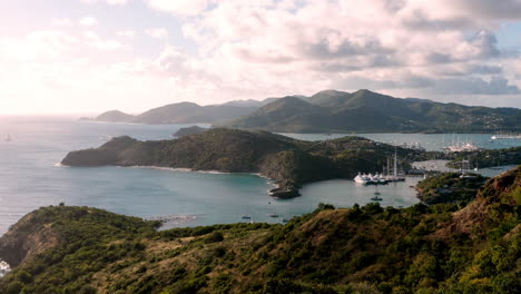 Toma-Aérea-De-La-Puesta-De-Sol-En-Puerto-Inglés-En-Antigua,-Caribe-Con-Vistas-De-Yates,-Veleros,-Puerto-Deportivo,-Bahía-Y-Acantilados