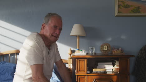 senior man sitting on bed at home