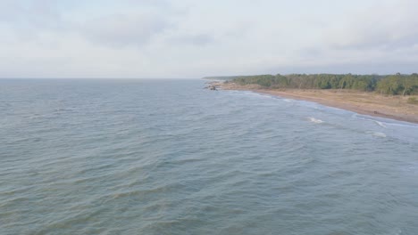 Vista-Aérea-Del-Muelle-De-Hormigón-Del-Puerto-De-Liepaja,-Día-De-La-Costa-Del-Mar-Báltico,-Grandes-Olas-Salpicando,-Tiro-De-Drones-En-Cámara-Lenta-Moviéndose-Hacia-Atrás