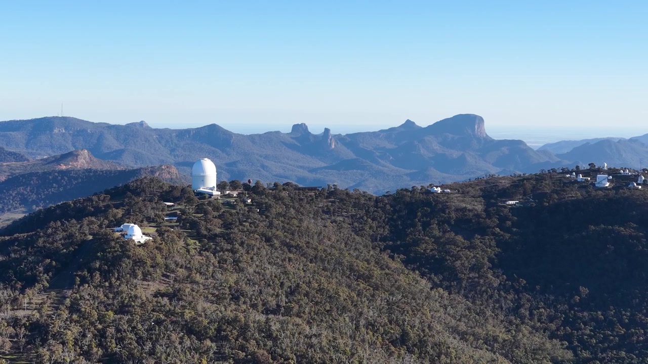 Inquadratura ampia di cupole di telescopi su una cresta montuosa nel Parco Nazionale Warrumbungle, Australia