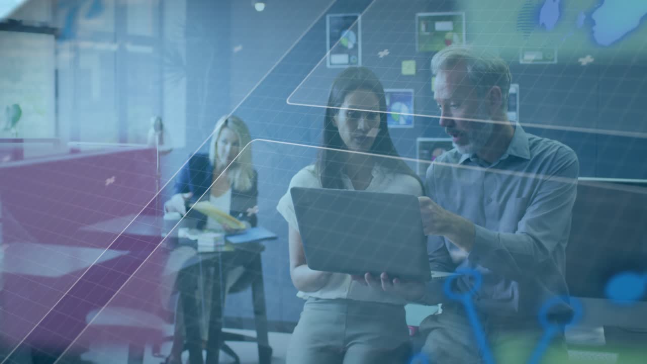 Man leaning in and pointing at laptop, mentoring colleague while tech maps and grids overlaying