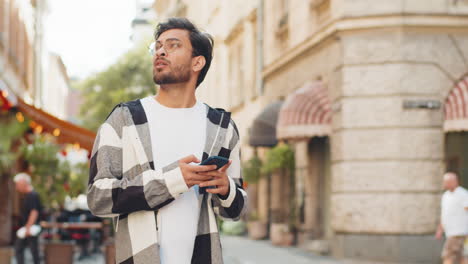 tourist man using smartphone looking for search way on map in mobile navigator app on city street