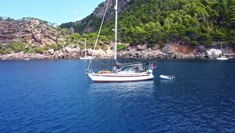 Sailing-lifestyle,-moored-vessel,-rocky-peninsula-location,-aerial-parallax