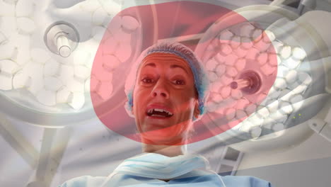 animation of flag of japan waving over female anesthesiologist in operating theatre