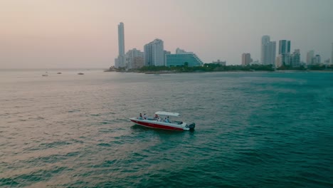 Aerial-Shot-of-a-boat-in-the-ocean-looking-the-sunset-in-Cartagena,-Colombia