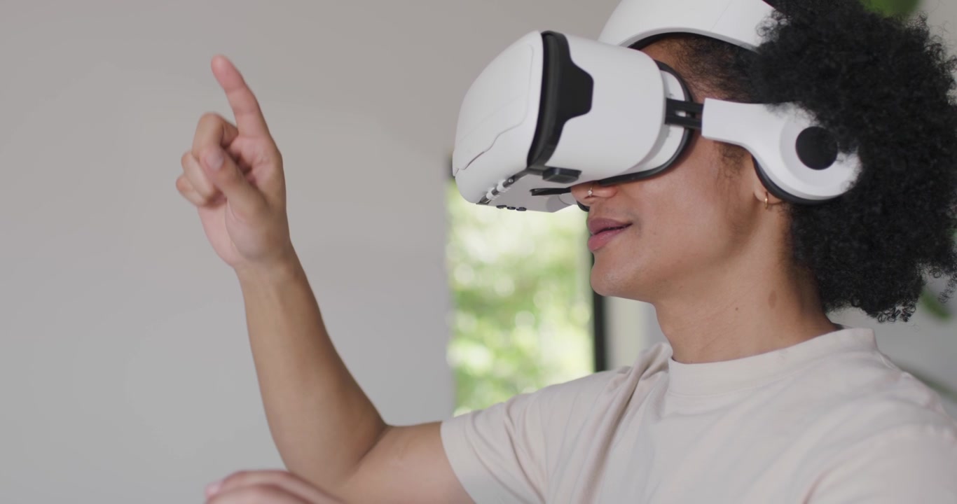 Uomo che indossa un visore VR bianco, usando la VR, indicando, pizzicando vicino alla finestra, cinturini di orologi, spazio per il testo