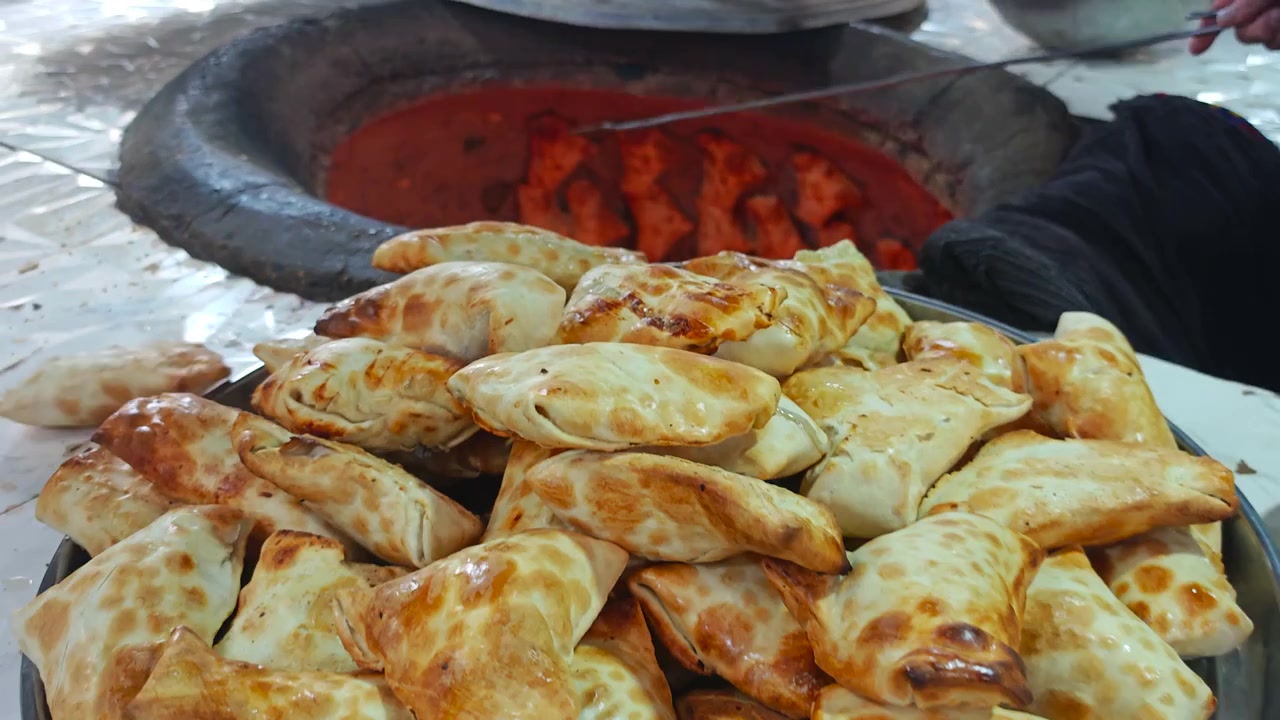 Fornaio che rimuove samsa appena sfornati da un tradizionale forno tandoor