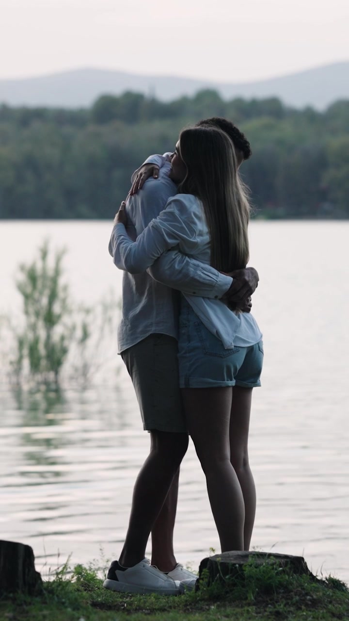 Giovane coppia romantica che si abbraccia in riva a un lago sereno