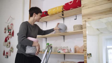 Craft-woman-shelving-wool-ball-on-rack-in-textile-shop.-Woman-in-textile-shop