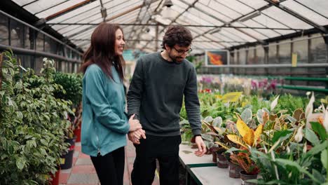 joven pareja romántica viendo flores en un jardín disparado