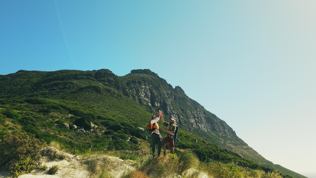 Due uomini che festeggiano un traguardo durante un'escursione su una montagna verde