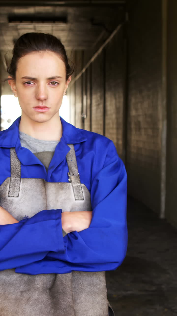 Female welder standing with arm crossed in workshop