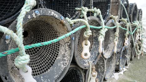 fishing harbour group of stacked lobster pots on coastal marine waterfront close up dolly right