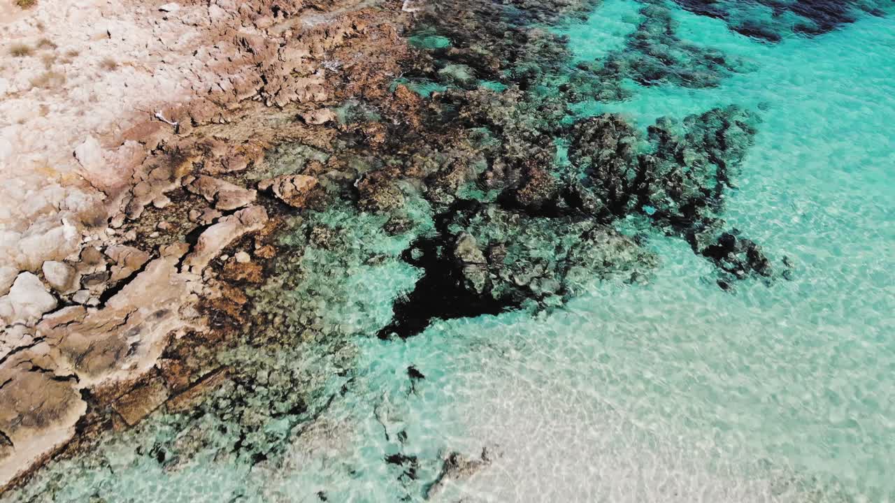 Ripresa aerea bassa con drone che esplora un misto di costa rocciosa di Maiorca e le acque limpide e blu del Mediterraneo.