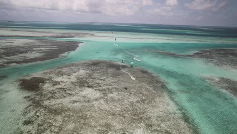 kite surfers gliding over turquoise waters in a tropical setting, aerial view