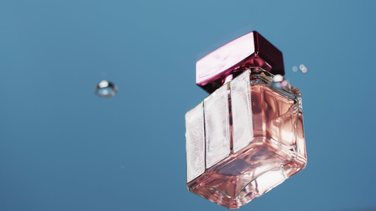 Video di una bottiglia di profumo che galleggia nell'acqua con spazio per il testo su sfondo blu