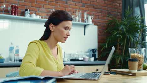 mujer de negocios exitosa usando una computadora portátil en la cocina. mujer recibiendo un buen mensaje