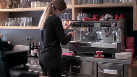 barista with face mask is working on the coffee machine in a restaurant