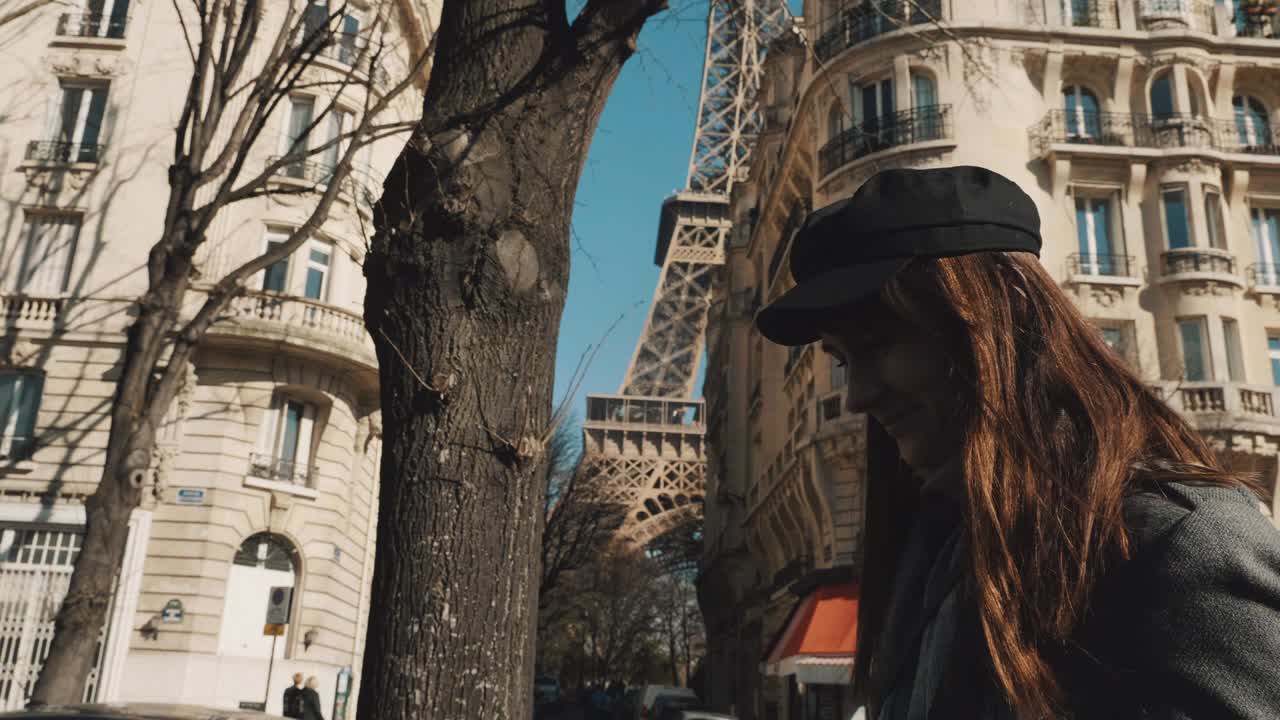 Tomada cinematográfica de mulher elegante e feliz sorrindo, caminhando pela rua de Paris, Torre Eiffel ensolarada ao fundo em câmera lenta