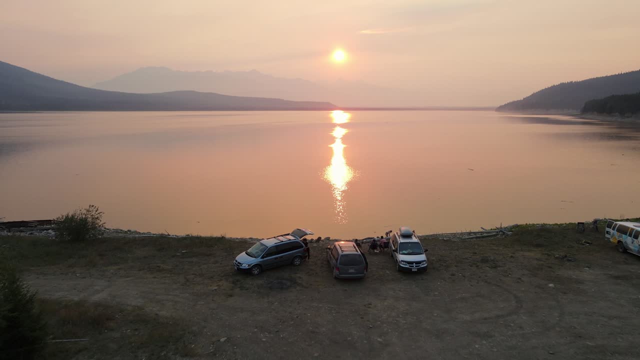 카누를 타고 캠핑하는 여행객들은 황금빛 해가 지고 캐나다 브리티시 컬럼비아의 산불을 겪는 동안 놀라운 킨바스켓 호수와 로키 마운틴 에 도착합니다.