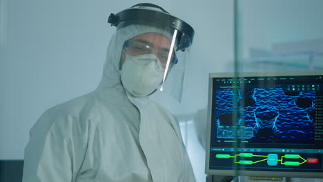 microbiólogo en traje de ppe de pie en el laboratorio mirando a la cámara