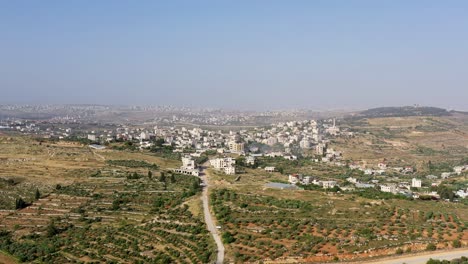 aerial view of a middle eastern village in a hilly landscape with olive groves