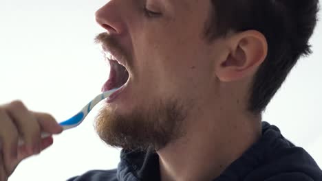 Close-up-shot-of-a-young-man-against-white-background-brushing-teeth