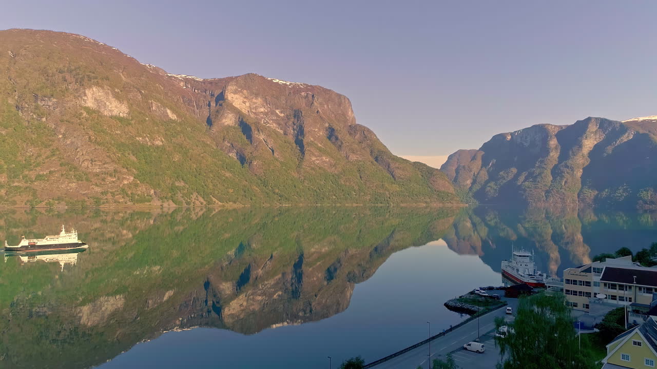 vuelo aéreo sobre un fiordo tranquilo con un barco de conducción durante la puesta de sol y la reflexión sobre la superficie del agua