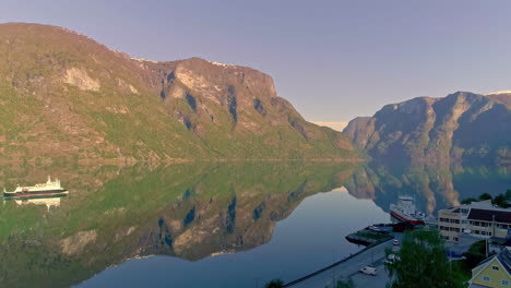 Luftflug-über-Einen-Ruhigen-Fjord-Mit-Fahrendem-Schiff-Bei-Sonnenuntergang-Und-Spiegelung-Auf-Der-Wasseroberfläche