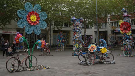 colorful artistic display of recycled flowers and bicycles in a vibrant urban space, showcasing creativity and sustainability through unique sculptures
