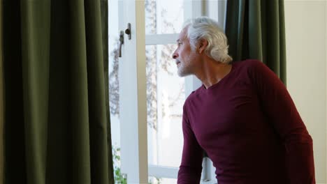 Senior-man-looking-through-window-in-bedroom-4k